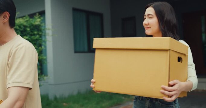 Young Asian couple carries cardboard boxes to load car trunk while moving out. Family relocation home mortgage loan, Real estate moving transport vehicle, New house package delivery pack concept.