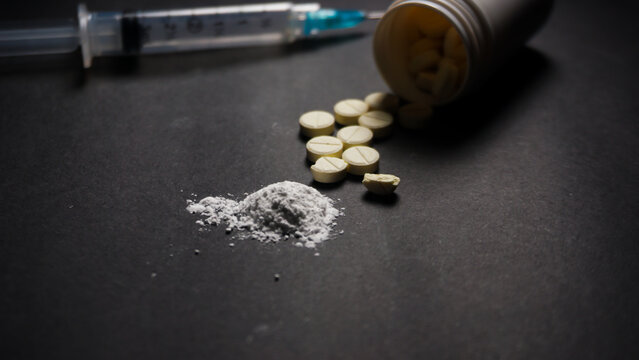 drugs. Some pills, white powder and a syringe behnd it. Misused drugs concept. 