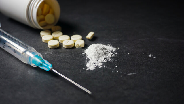 syringe, pills and white powder of crushed pills. Misused drugs concept. 
