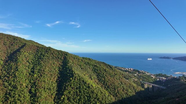 Forested hillside above coastal town with distant ship. View of Rapallo Italy from cable car