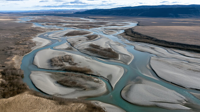 Braided river winding through arctic tundra with sandy islands and distant mountains