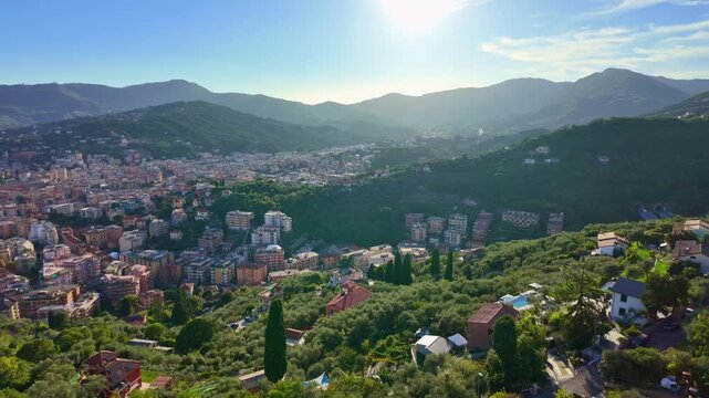 Hillside town nestled in a green valley with distant mountains. Rapallo view from moving cable car in Italy