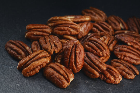 Macro shot of fresh premium pecan nuts with selective focus on grey background with artistic lighting. Perfect for healthy eating, gourmet food, culinary, and dietary content.