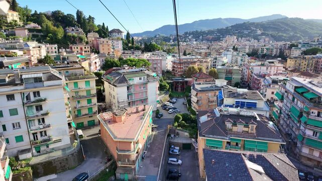 Colorful hillside apartment buildings in residential neighborhood. Rapallo view from moving cable car in Italy