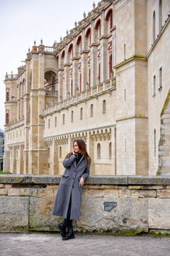 Woman in gray coat beside Saint-Germain-en-Laye Chateau wall