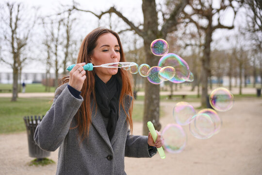 Woman blowing colorful soap bubbles in a Saint-Germain-en-Laye park