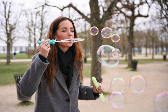 Woman blowing soap bubbles in a Saint-Germain-en-Laye park