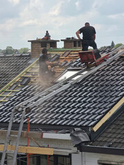 Ouvriers qui rénovent la toiture d’une maison pour isolation et remplacement des tuiles © joef