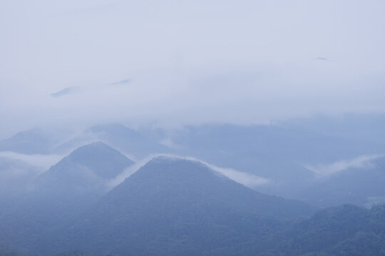 Moody atmospheric view of rolling mountain ranges covered in thick fog after summer rain, Tranquil Japanese highland scenery offering a sense of mindfulness, zen and natural beauty for wellness concep