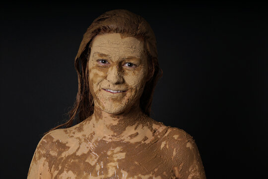 woman covered face hair and body with healing earth or medicinal clay or mud mask