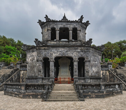 Ornate stone stele pavilion with intricate dragon carvings at the Khai Dinh Tomb in Hue, Vietnam, showcasing traditional imperial Vietnamese architecture against a dramatic sky