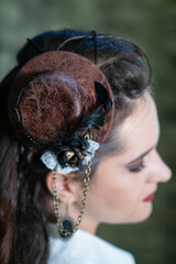 Steampunk Woman Wearing Mini Top Hat Fascinator with Feathers and Chains © Margarita