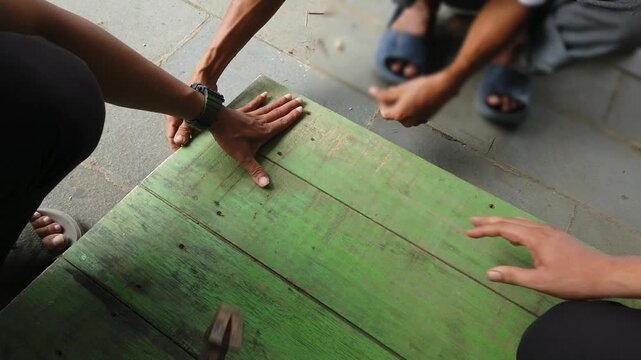 Two people helping each other with carpentry work by holding wooden boards and hammering nails into the wood. The image represents teamwork, manual labor, construction, woodworking, cooperation, and p