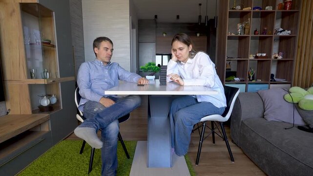 Couple playing a tense game of Jenga at a table, focusing on not knocking down the wooden tower. Concentration, family fun, and strategic thinking.