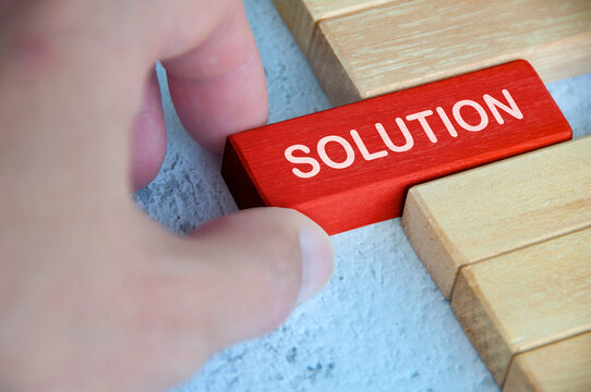 Hand placing red wooden block with solution text on other wooden blocks.