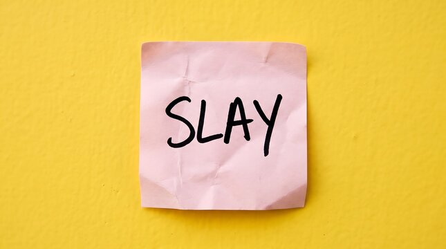 Slay handwritten text on pink sticky note, motivational slang message on crumpled paper, positive affirmation on yellow background