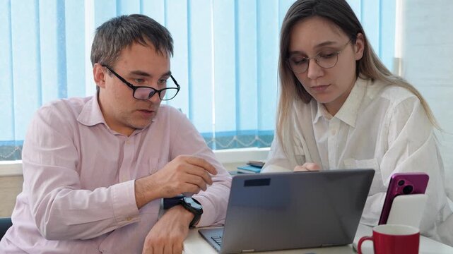 Female business manager consulting male client at office meeting with laptop.