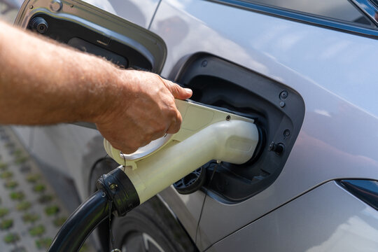 Close-up of a person plugging an electric car charging cable into the vehicle