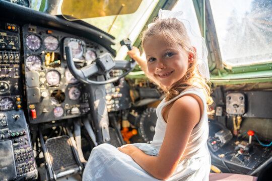 Young girl exploring airplane cockpit and holding flight controls. First aviation experience encourages childhood curiosity, learning and career dreams