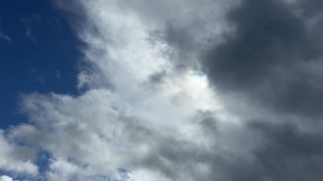 Dramatic dark storm clouds swallowing and covering soft white clouds in a contrasting blue sky with strong copy space