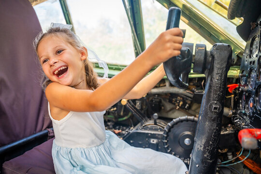 Young girl exploring airplane cockpit and holding flight controls. First aviation experience encourages childhood curiosity, learning and career dreams