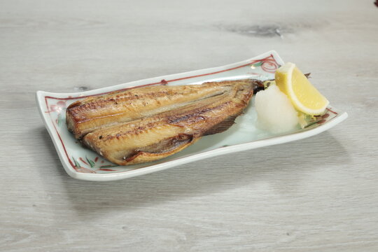 Delicious grilled fish garnished with lemon and daikon served on an elegant plate