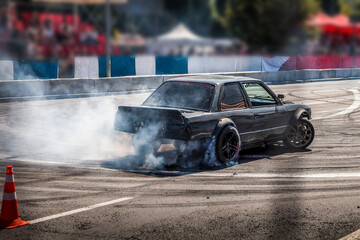 Drifting car creating smoke on a race track with spectators in background © shine.graphics