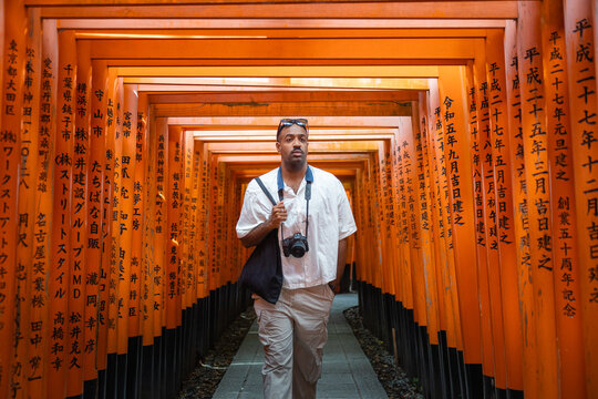 Tourist exploring traditional torii tunnel in Kyoto