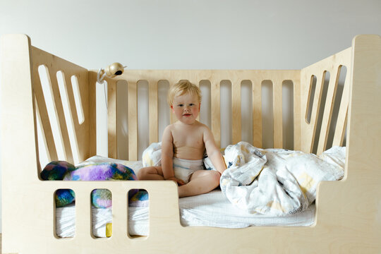 A small child sits in bed after sleeping