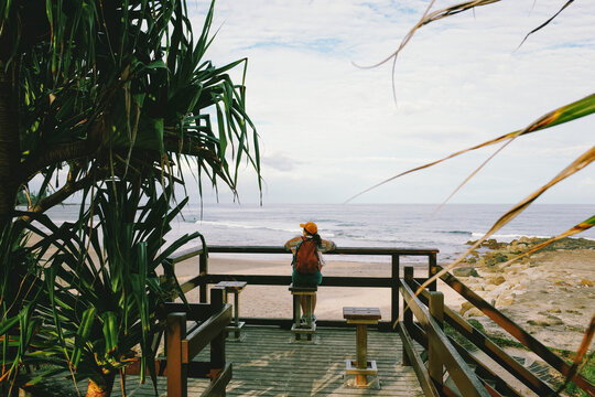 Woman with backpack looking out at the beach in Australia