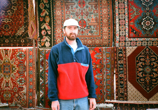 Man Standing in Front of a Display of Patterned Rugs