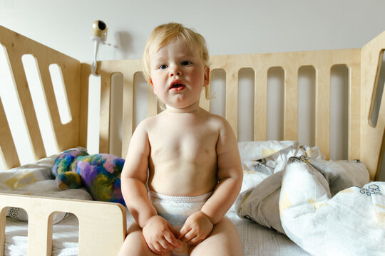 A small child sits in bed after sleeping