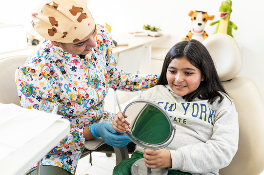 Smiling girl looking at reflection with dentist after checkup
