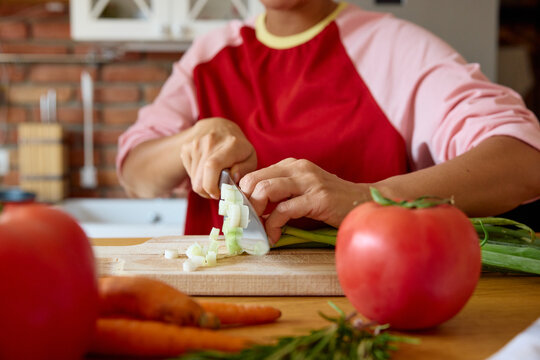 Woman chops fresh leeks in the kitchen.