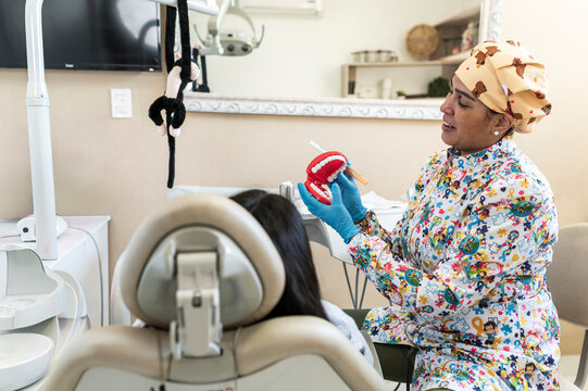 Pediatric dentist teaching oral hygiene with toy teeth model