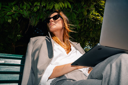 Woman Working on Laptop in Park on Sunny Day