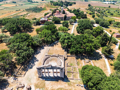 Apollonia Archaeological Park in Albania. Aerial drone view of ancient archaeological ruins with a preserved classical structure, stone foundations and amphitheater in a dry Mediterranean landscape.