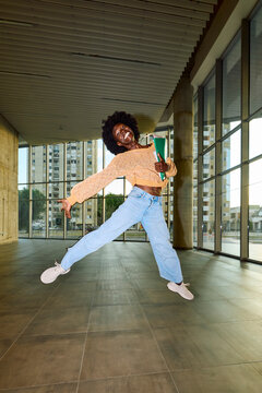 Woman jumps high carrying her learning material