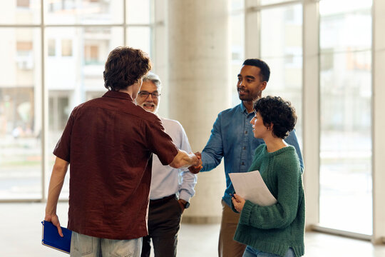 Professor and an assistant greet their students in the hallway