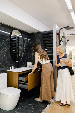 Client testing bathroom cabinet during design consultation