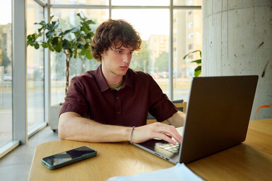Young Man Works on a Laptop in a Modern Workspace