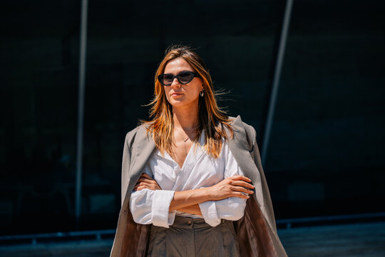 Woman in Sunglasses Stands Confidently Outside on a Sunny Day