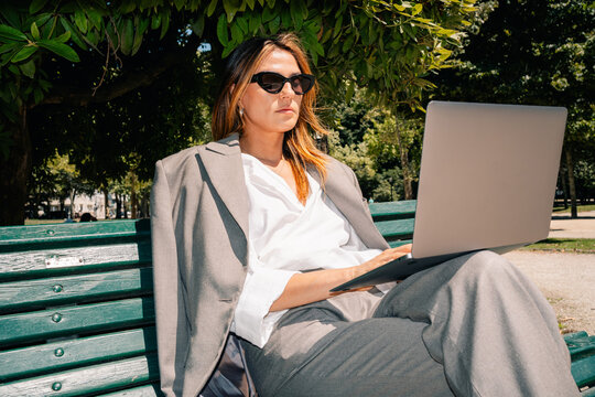 Woman Working on Laptop in Park on Sunny Day
