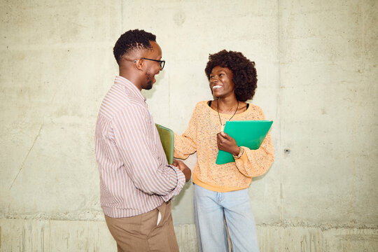 Two People Talk and Smile in a Building Hallway