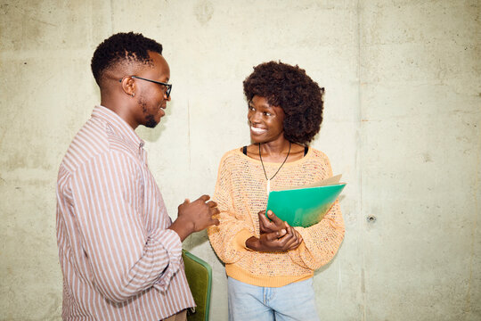 Two People Talk and Smile in a Building Hallway