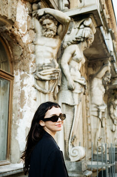 Woman Stands Near Historical Sculptures in an Old City Street