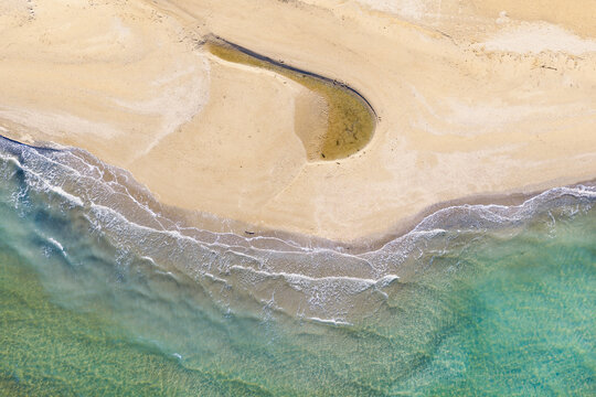 A small coastal lagoon on a sandy beach with gentle waves