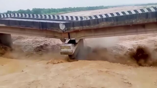 Bridge collapse due to the strong current of an overflowing river caused by heavy rains and flooding.