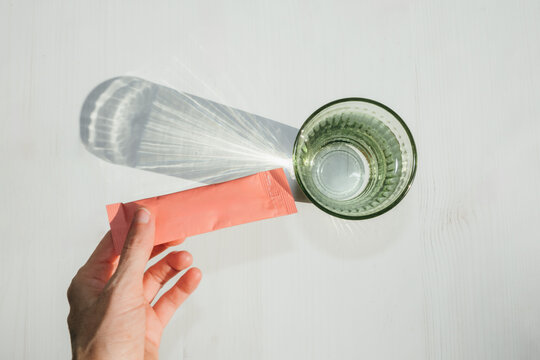 Hand Holding Electrolyte Powder Packet with Water
