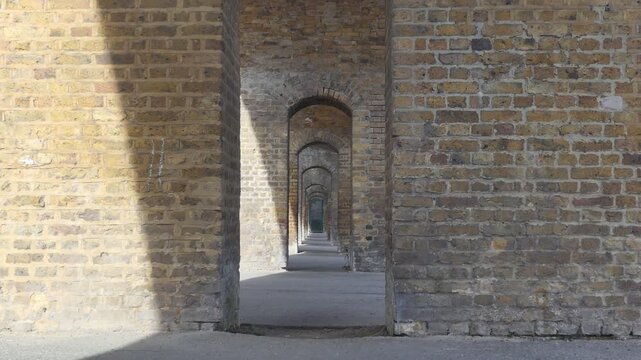 A perspective view through a series of repeating brick arches.